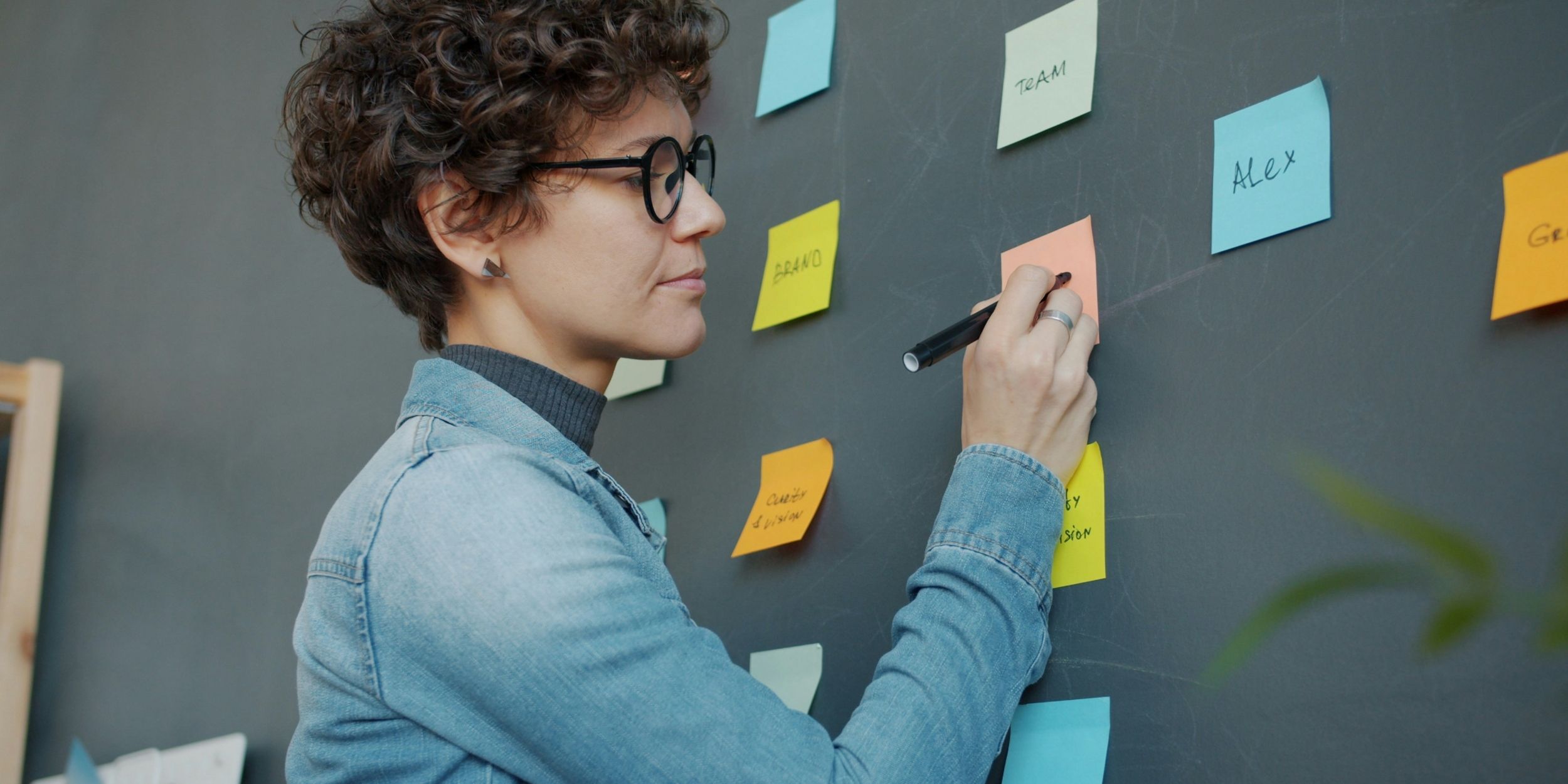 female digital strategist writes on a sticky note on the wall
