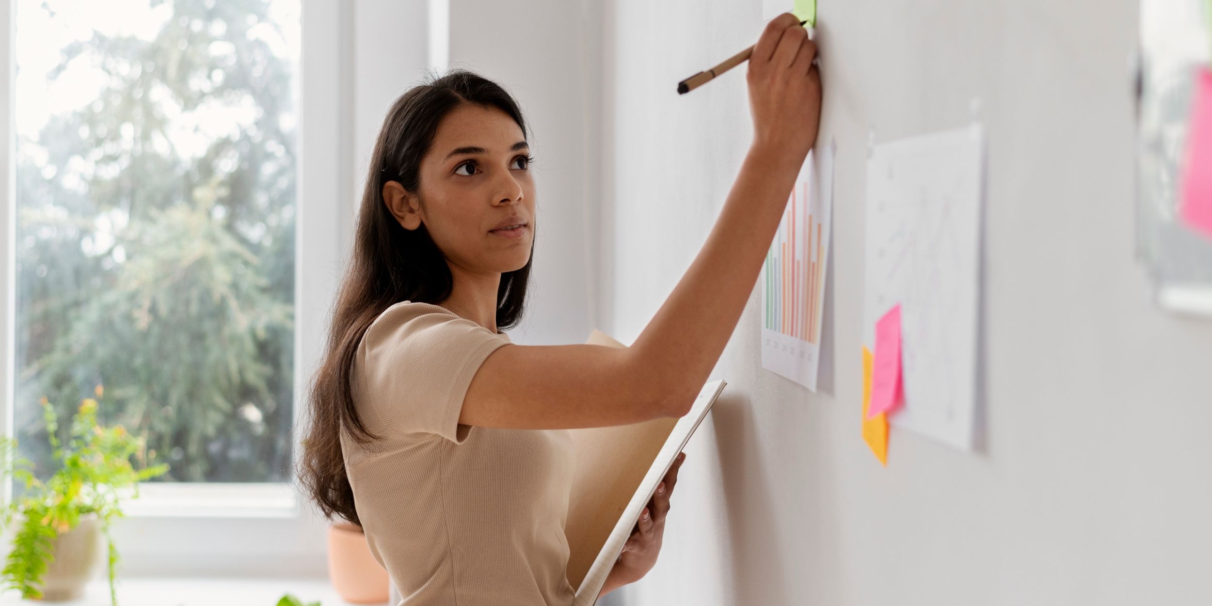 female strategist writes on whiteboard during a workshop